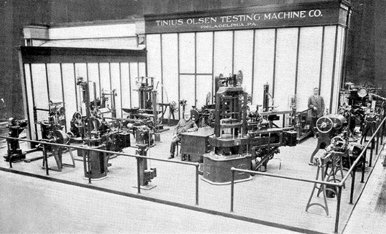 1915年旧金山的巴拿马-太平洋展会上展出的Tinius Olsen试验机  （图片ZY坐着的为Tinius Olsen先生本人）.png